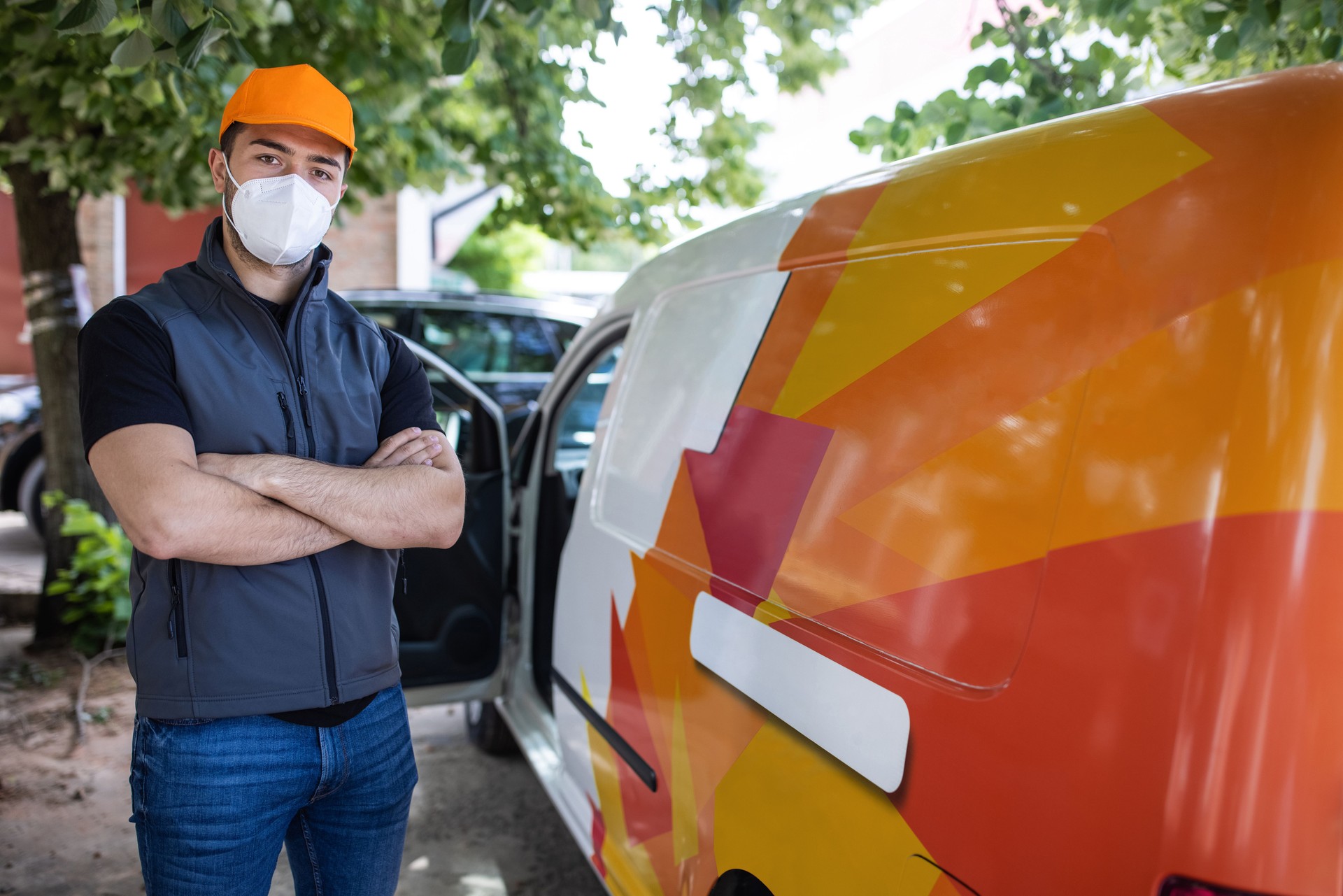 Portrait of delivery man with cap and protective face mask beside van